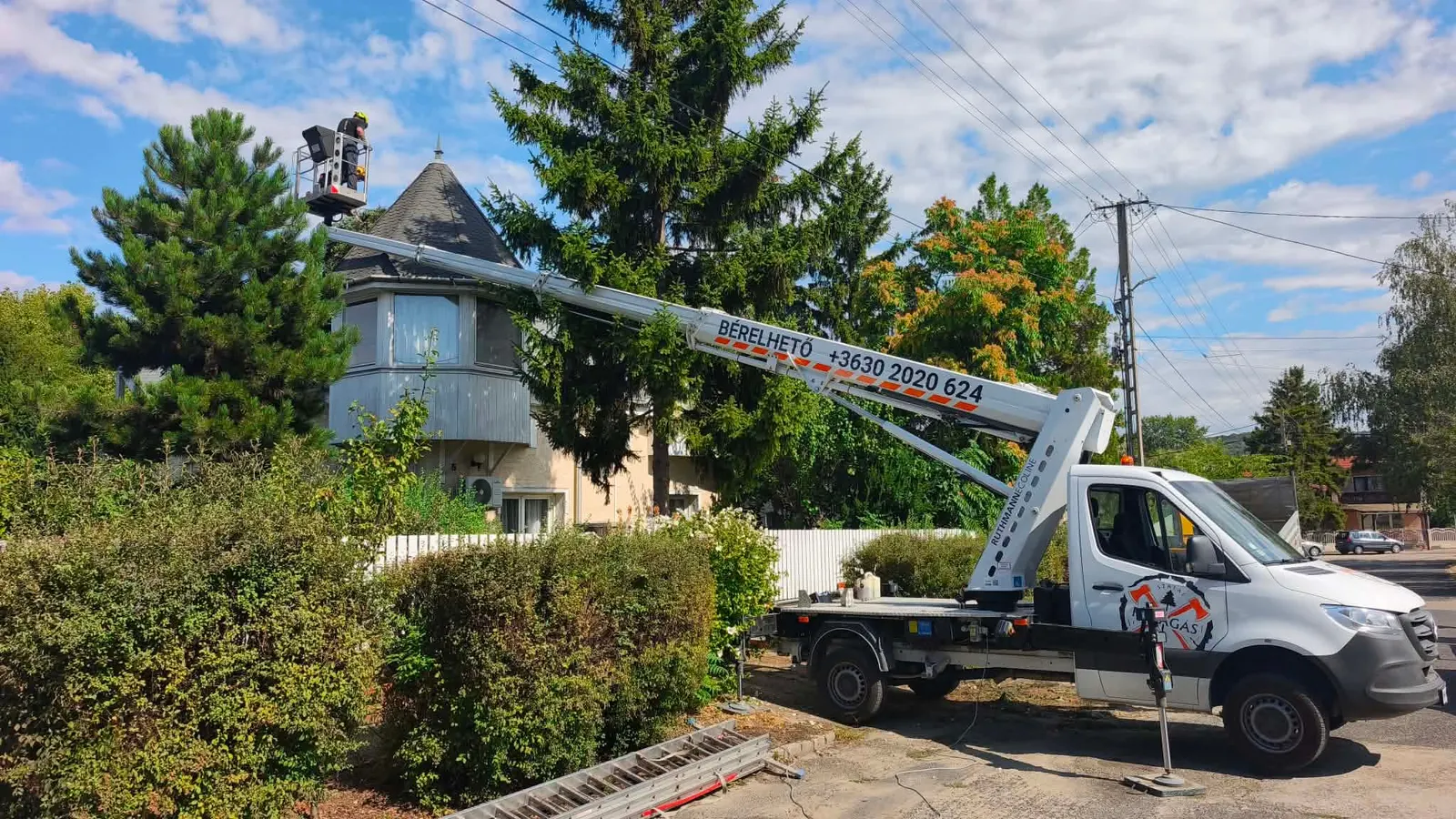 23 méteres emelőkosaras autó 16 méteres kinyúlással ház és fák fölött